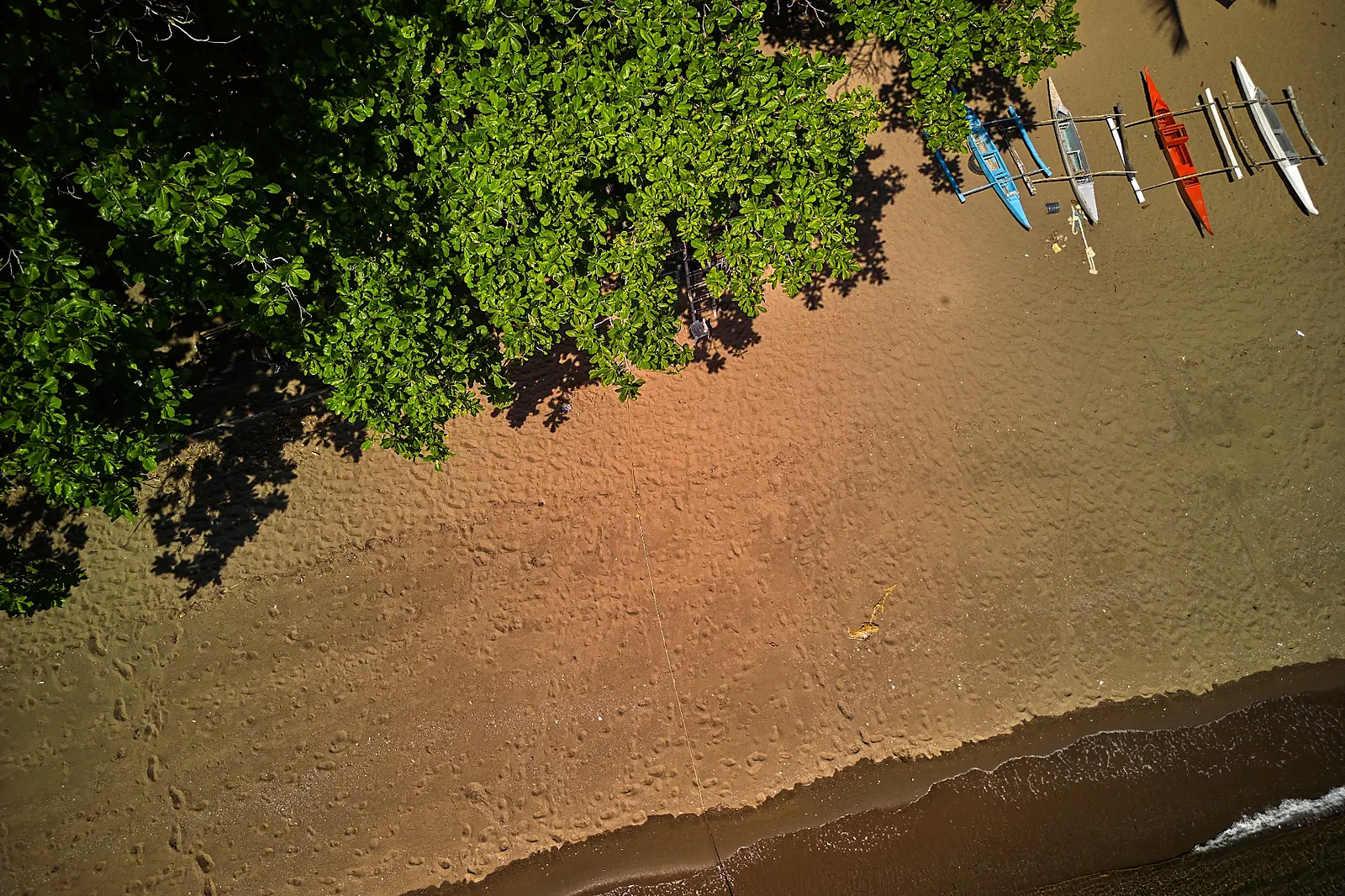 Overhead view of outrigger boats beside a sandy beach in Dauin