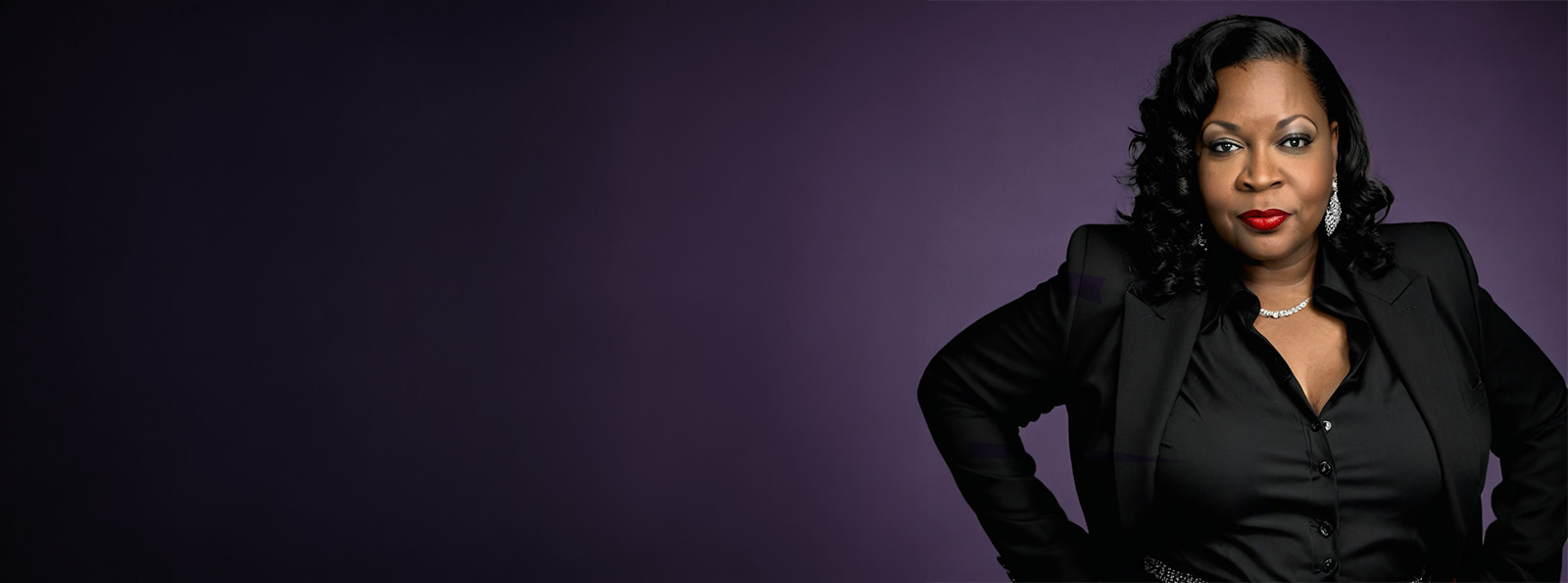 Chekema Hector in a black blazer against a deep purple studio backdrop