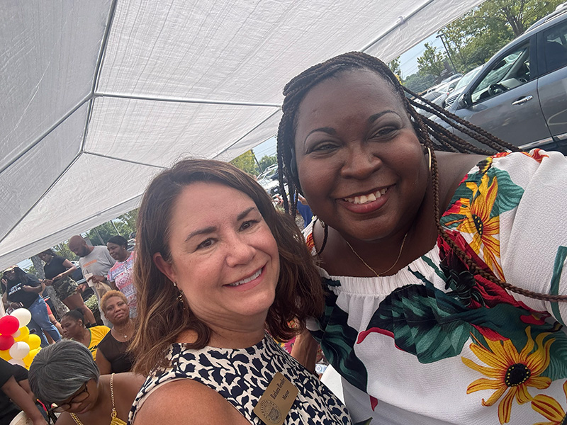 Chekema Hector with a guest under the tent at the Juici Patties Snellville grand opening