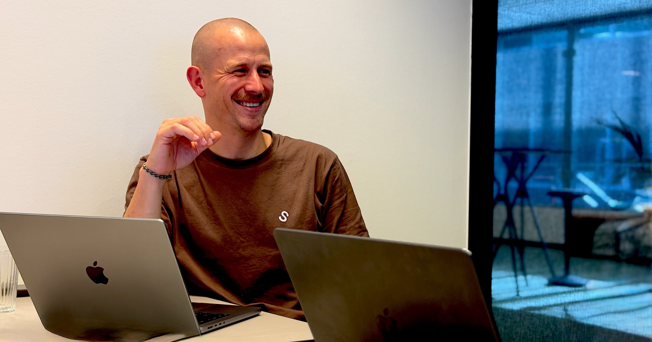 Mayker consultant smiling during a working session with a customer team, laptops open on the table.