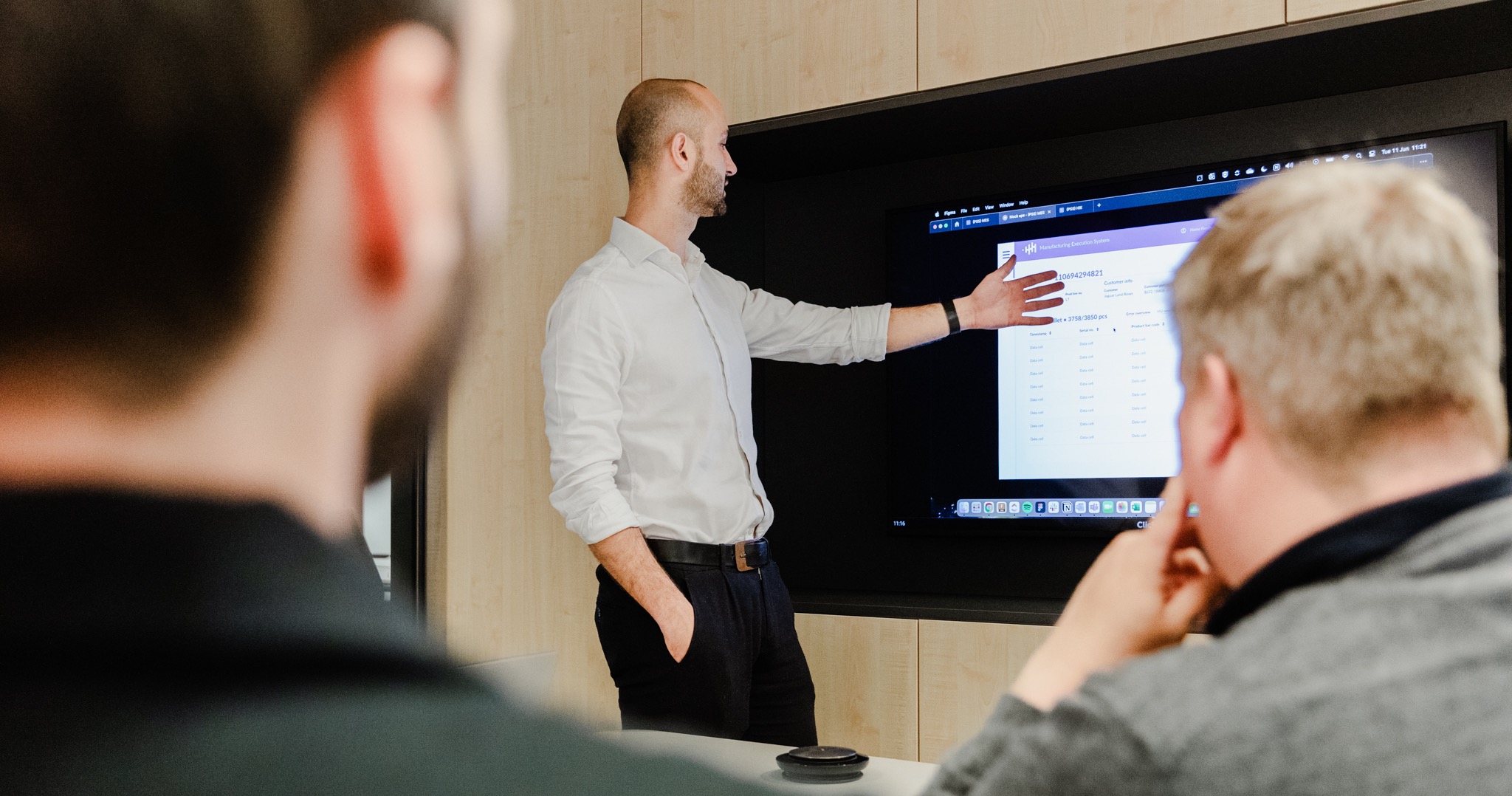Mayker consultant presenting a manufacturing execution system screen to colleagues in a meeting room.