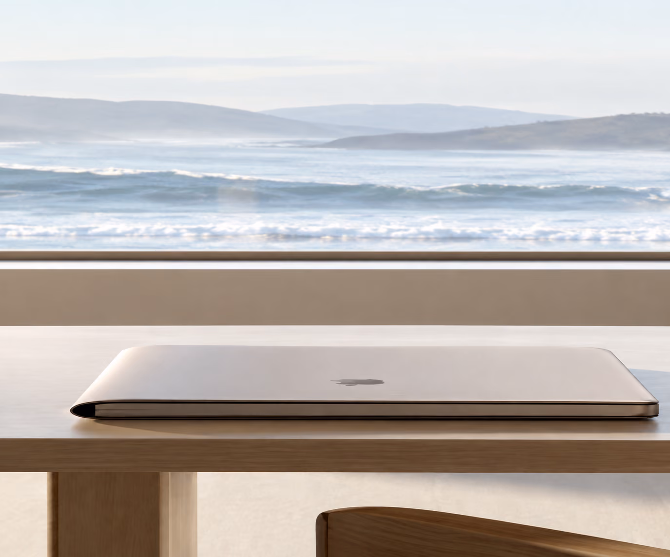 Ordinateur portable posé sur une table en bois face à l'océan
