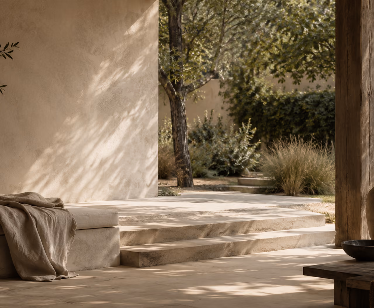 Patio méditerranéen minimaliste en pierre claire ouvert sur un jardin ombragé