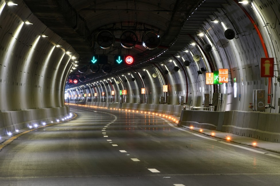 Interior of the Port Said road tunnel in Egypt, showing illuminated lanes, overhead traffic signals and emergency safety signs.