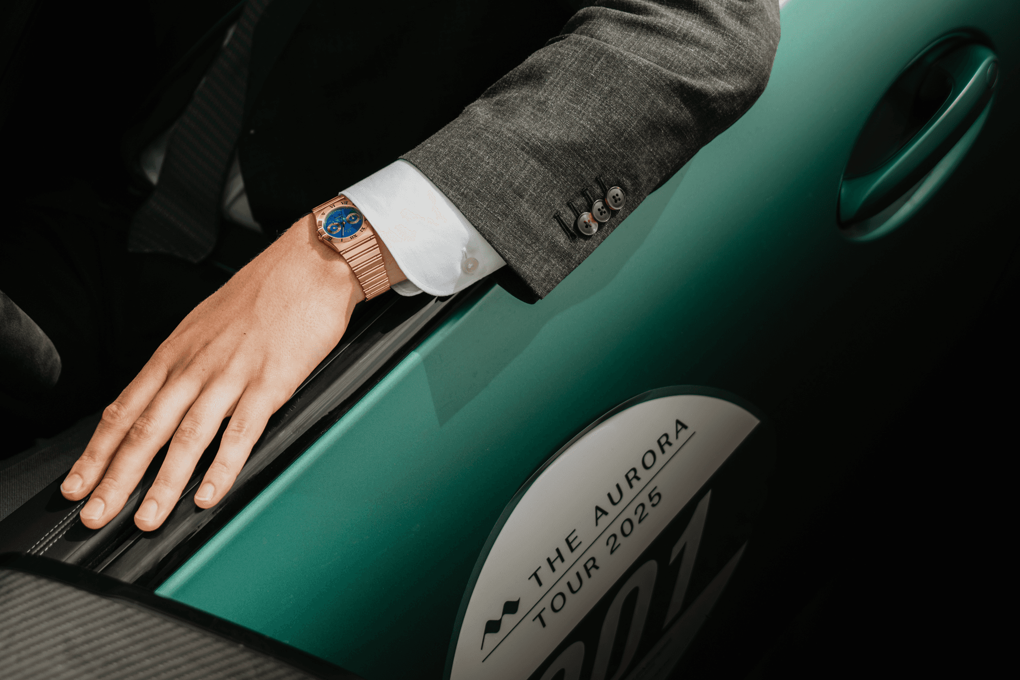 A hand on an evergreen race car door marked The Aurora