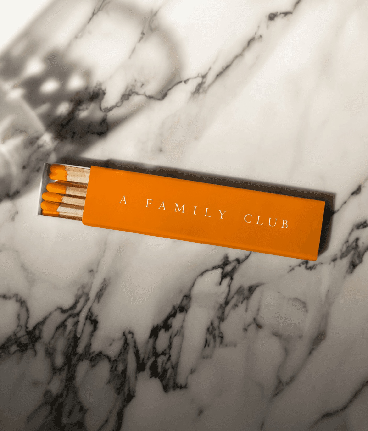 An orange A Family Club matchbox on marble