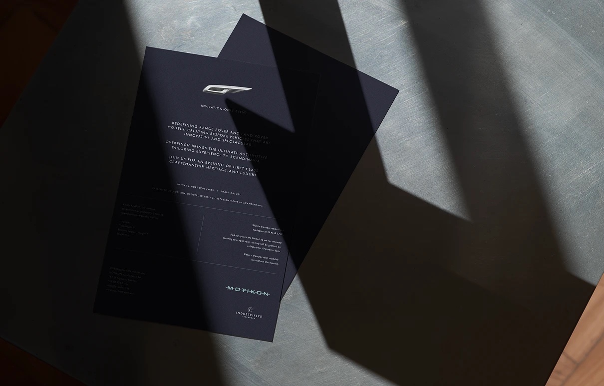 Printed Overfinch invitations in dark navy on a stone table