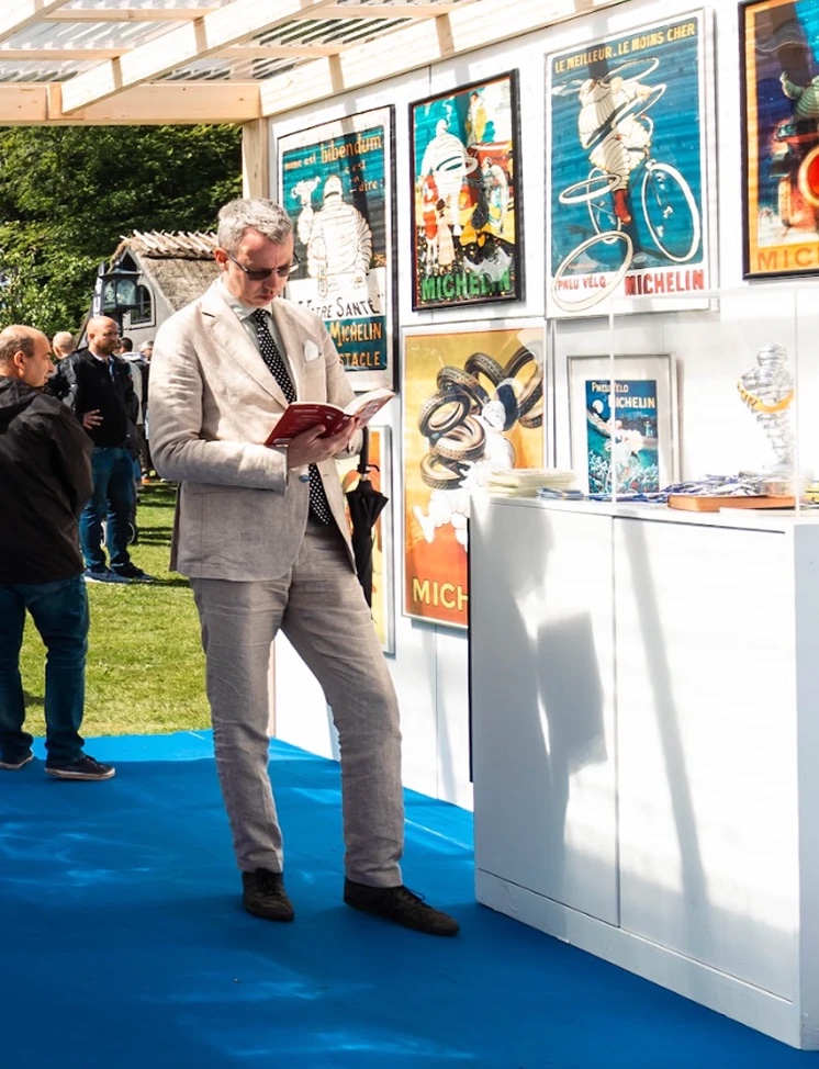 A visitor reading a Michelin Guide in front of the vintage poster wall
