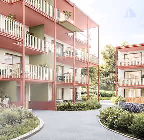 Blick auf moderne, rosafarbene Wohnblocks mit Balkonen, umgeben von geschwungenen Wegen und grünen Sträuchern unter einem klaren Himmel.
