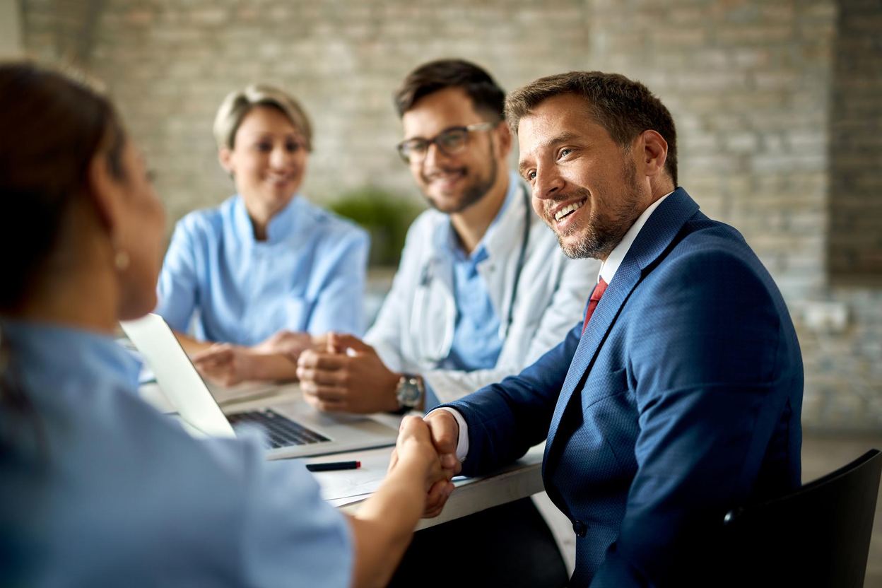 Physician and advisors shaking hands at a meeting