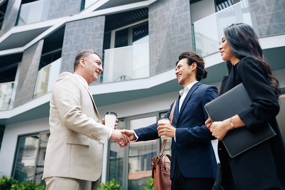 Advisers greeting clients outside a modern residential building