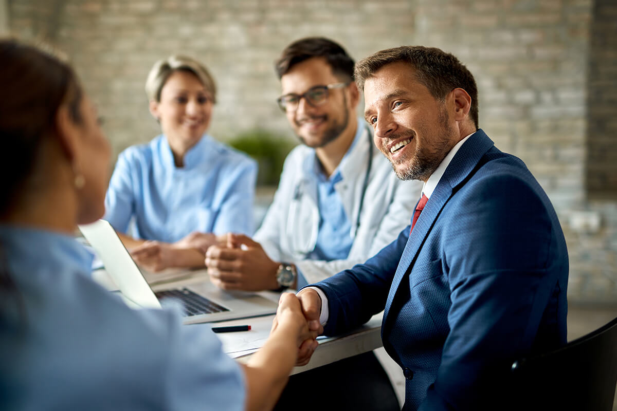 A physician and a clinical colleague meeting with an adviser across a conference table