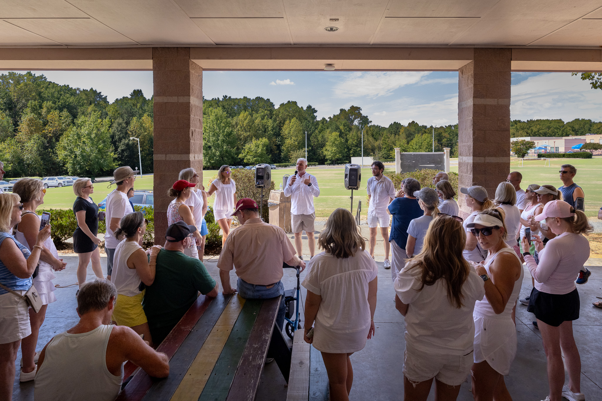 Community members gathered under an outdoor pavilion listening to a speaker