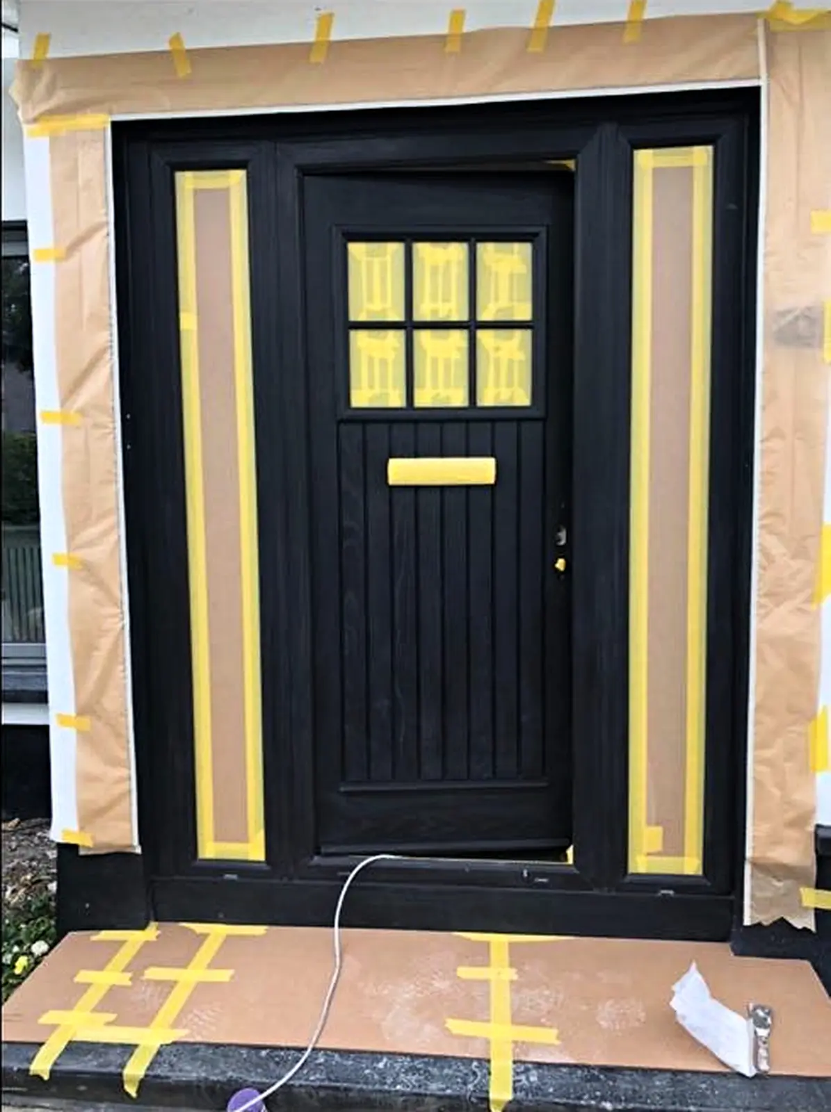 Front door and sidelights masked during spray painting preparation