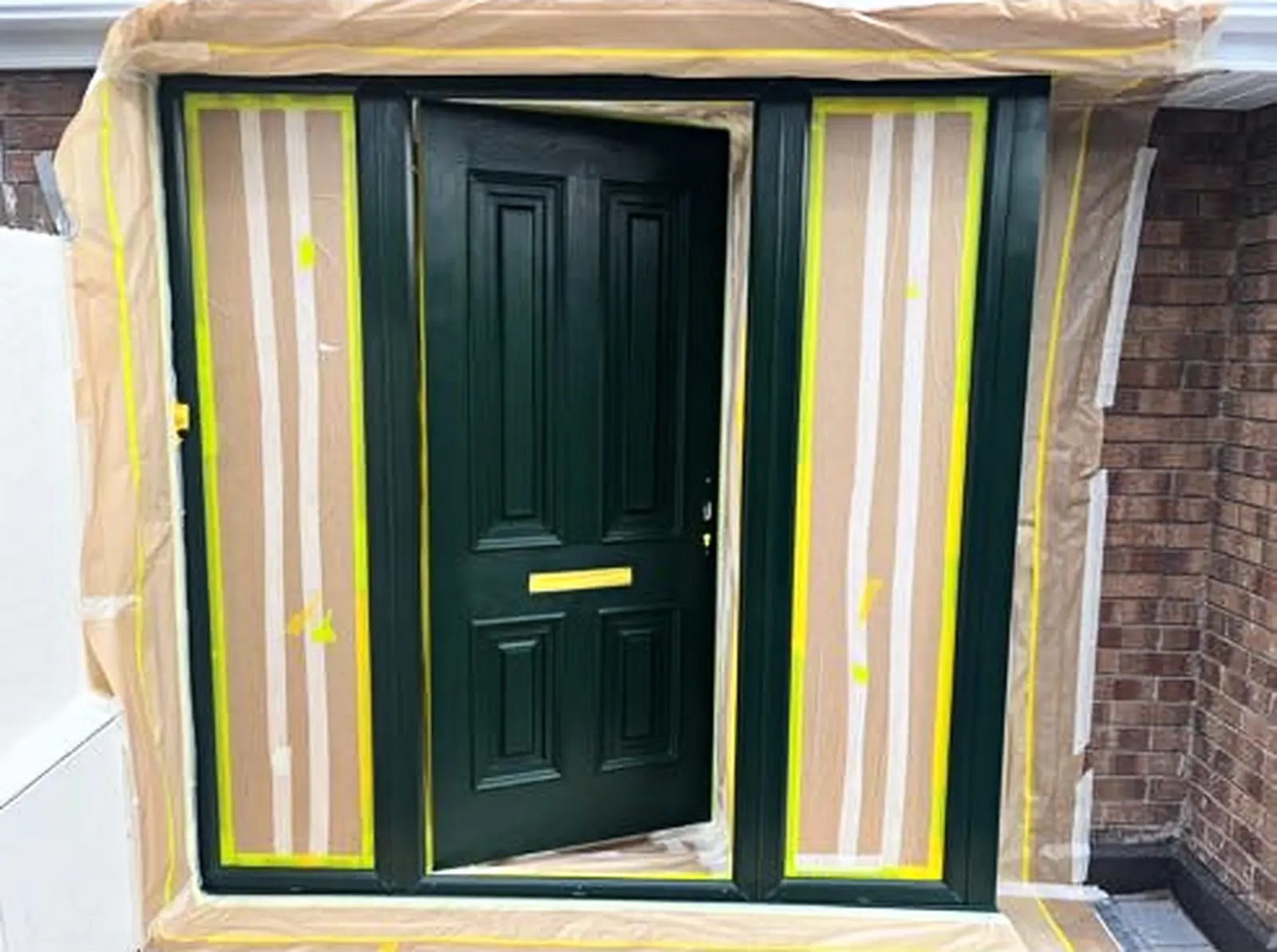 Green front door masked and prepared during spray painting