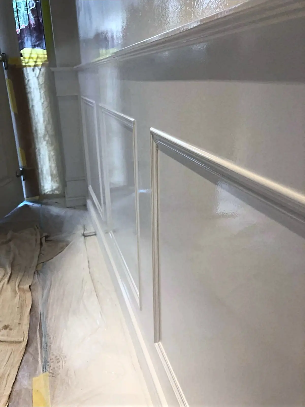 White timber wall panelling protected during painting