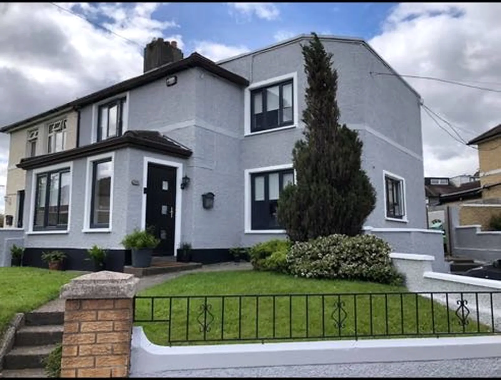 Completed grey exterior painting with white detailing and dark trim