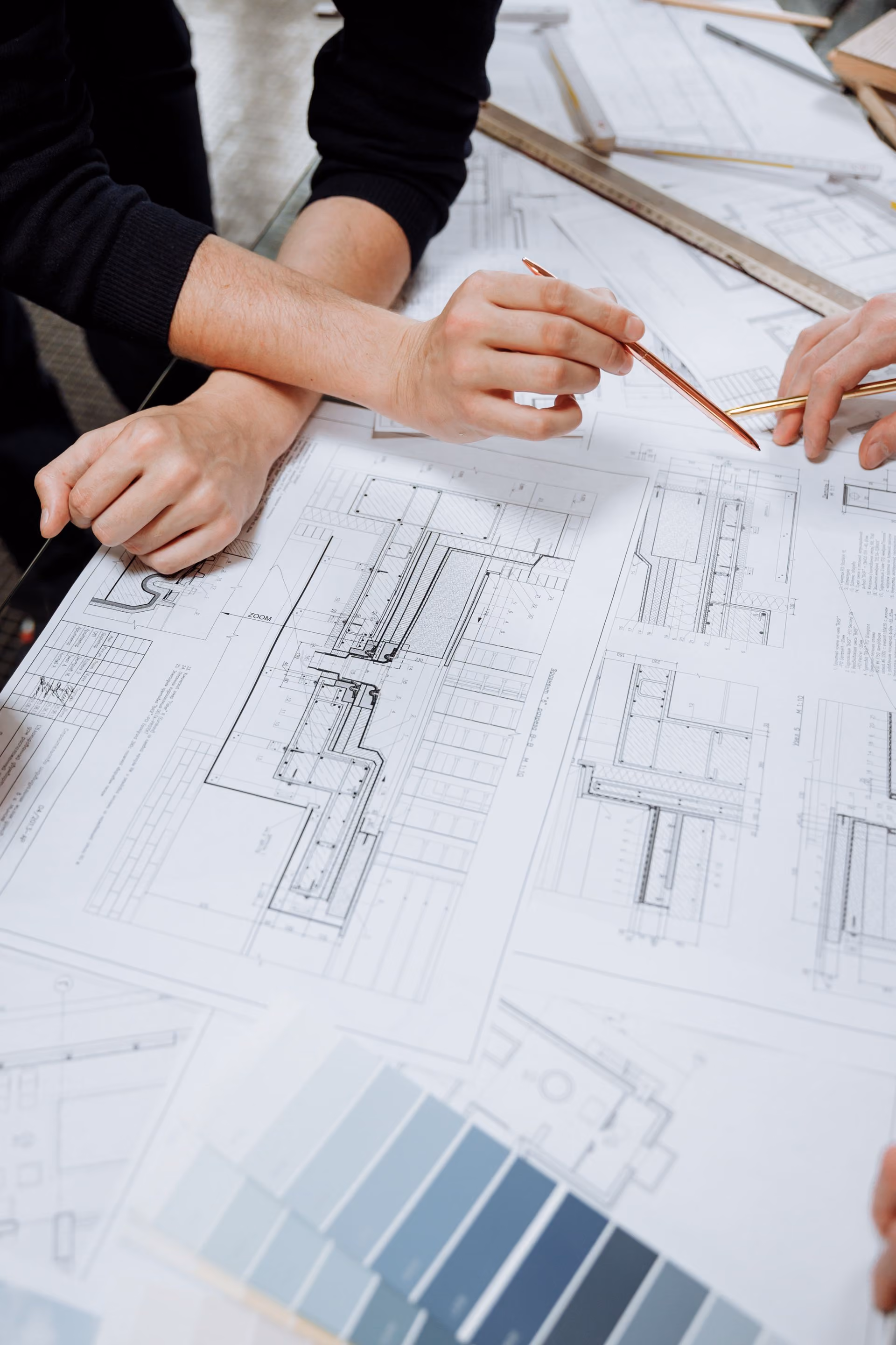 Mains d'architectes sur des plans, avec des échantillons de couleurs et de matériaux