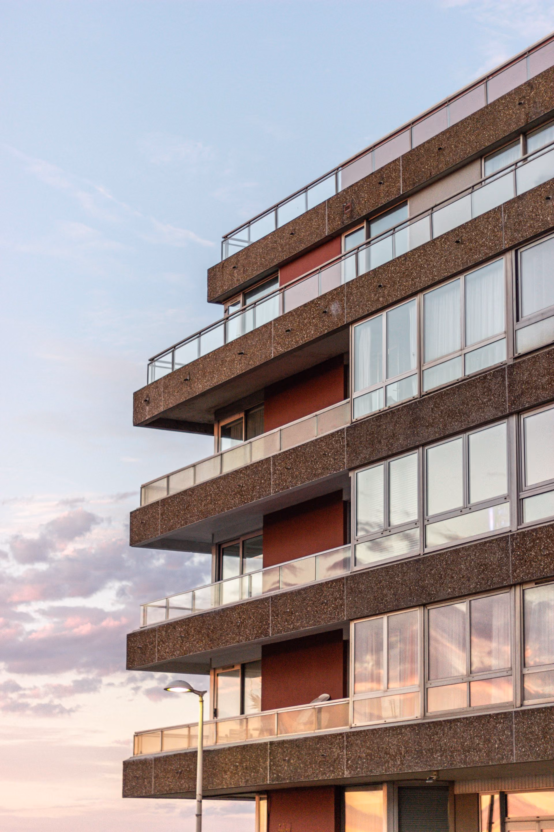 Immeuble résidentiel moderne aux balcons rouges, vu en contre-plongée au coucher du soleil