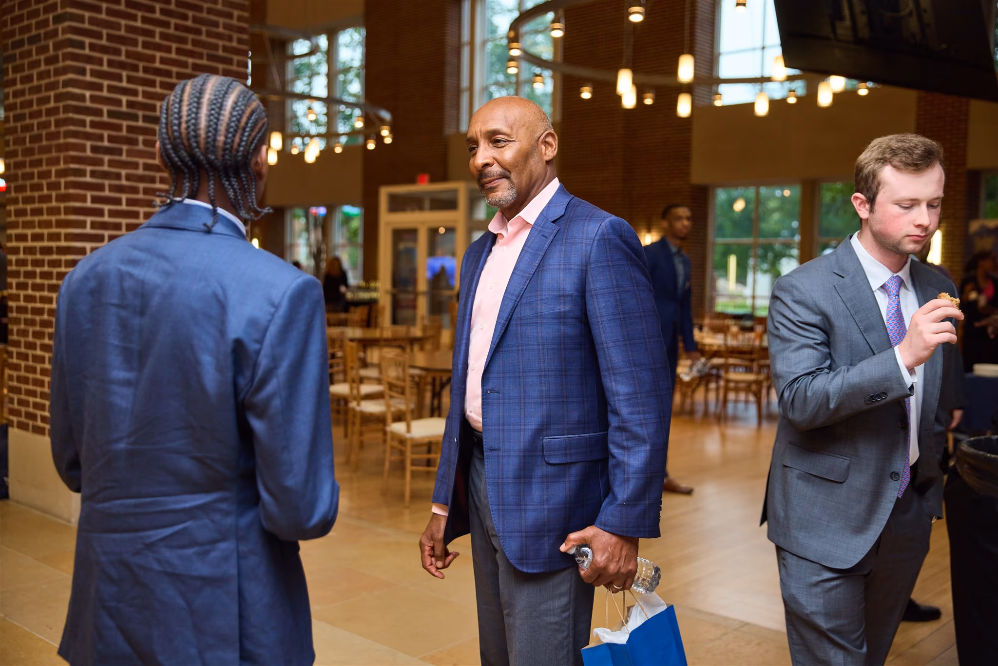 Guest speaker in a blue blazer chatting with students at a reception