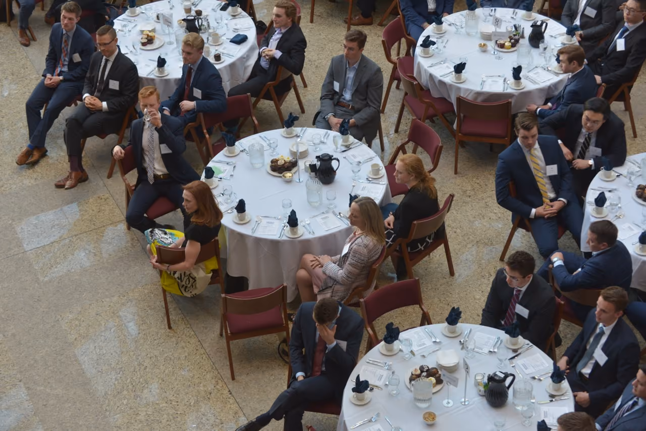 Overhead view of students and professionals seated at round banquet tables in an atrium