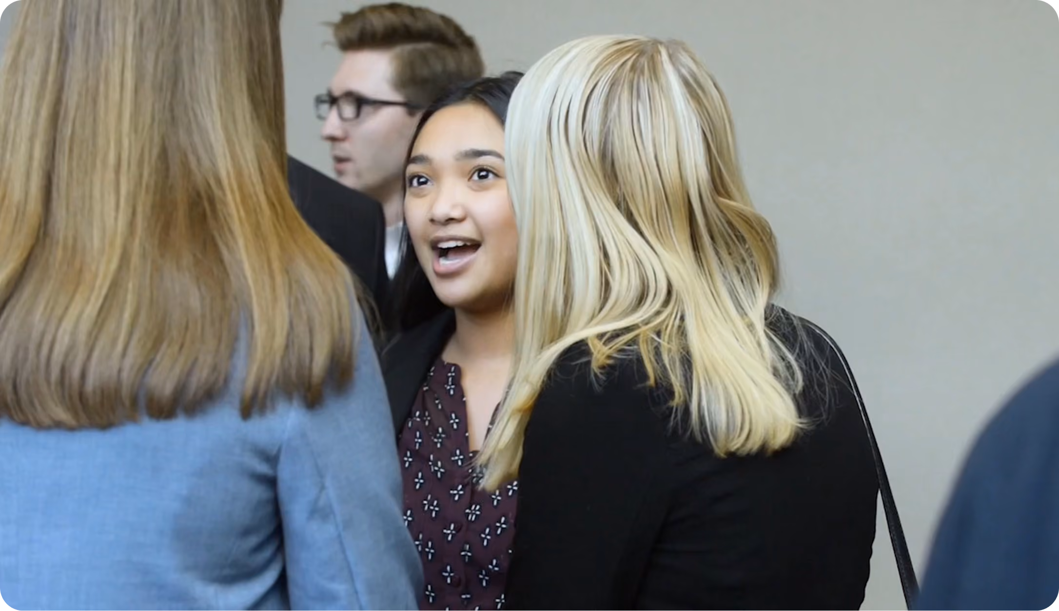 Students in professional attire talking with one another at a networking event