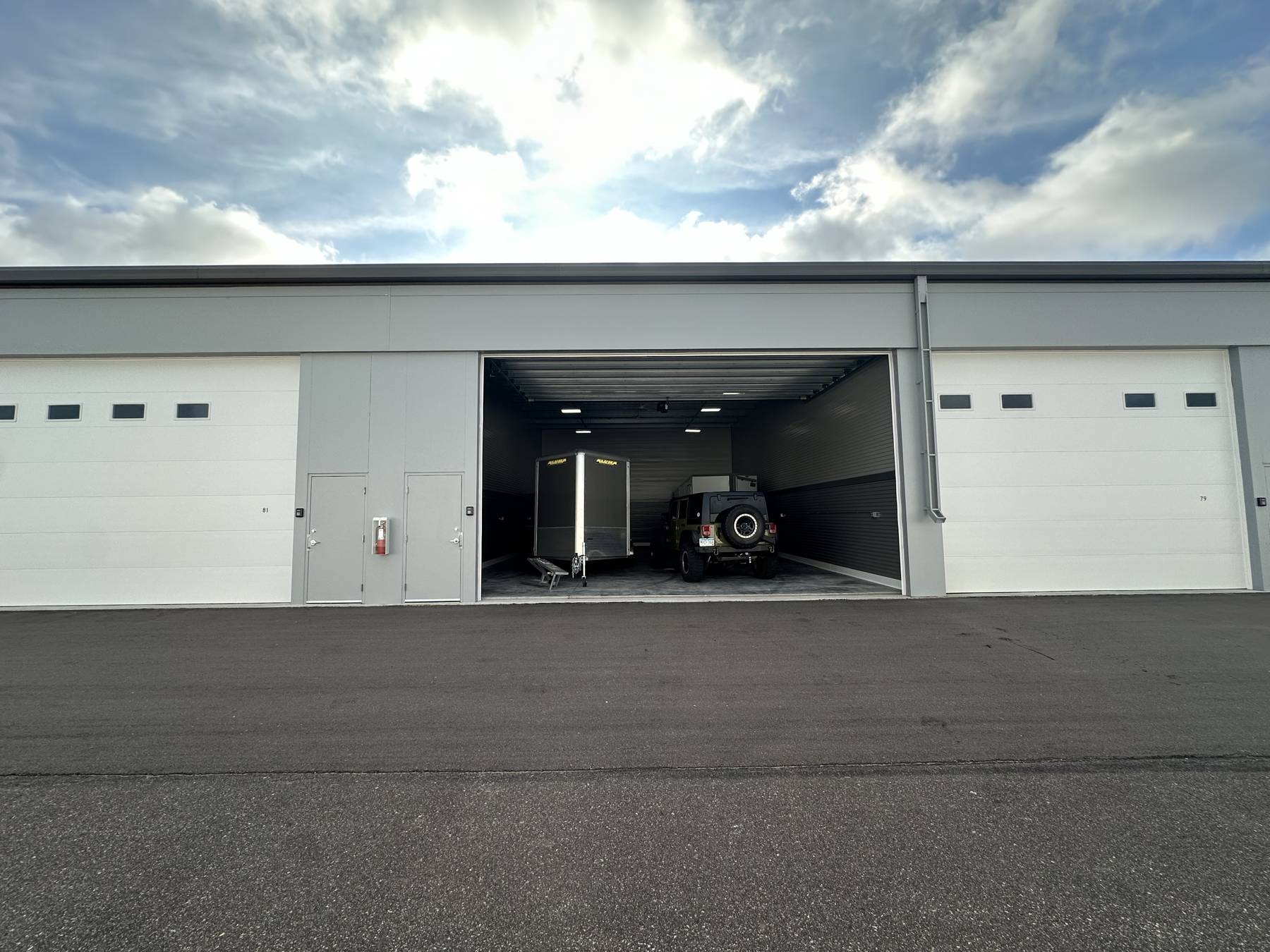 An open Park Place Storage garage with a trailer and Jeep parked inside