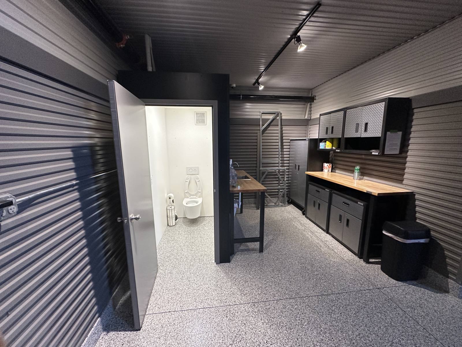 Utility sink and workbench next to a private bathroom