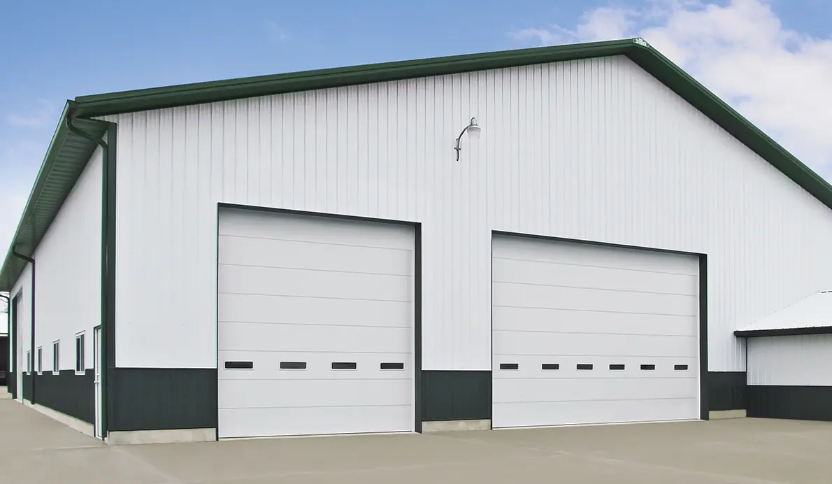 White industrial building with two large white commercial garage doors.