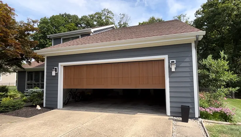 Partially open residential wooden garage door on a gray house with white trim.