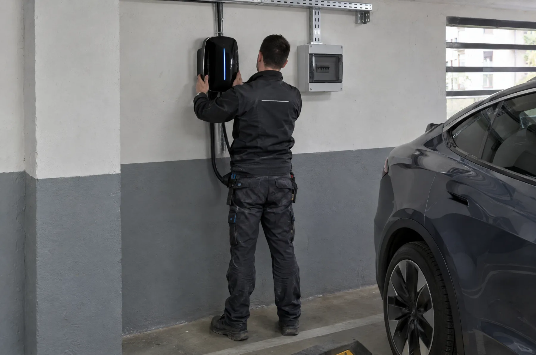 Električar ugrađuje zidni punjač u garaži stambene zgrade