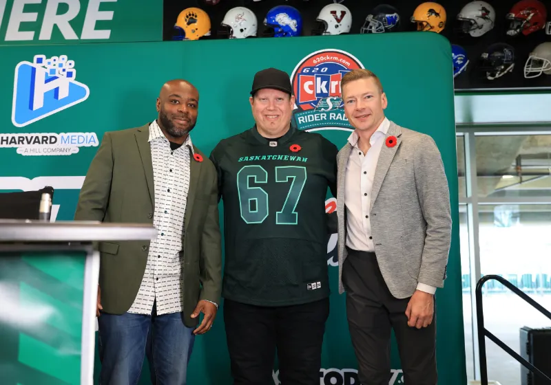 Three hosts in front of the 620 CKRM Rider Radio backdrop