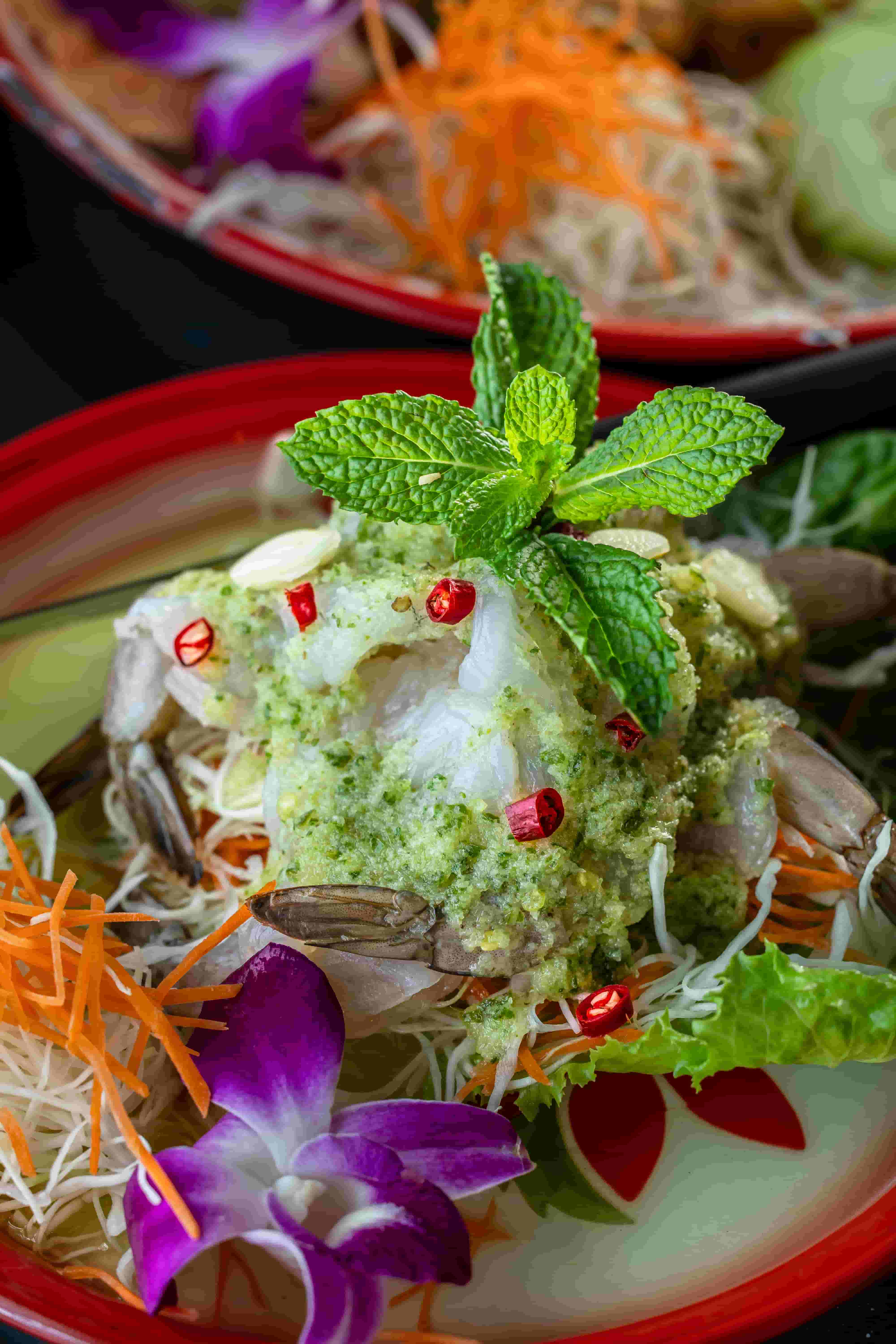 Raw shrimp in green chili and garlic sauce with mint, shredded carrot and an orchid