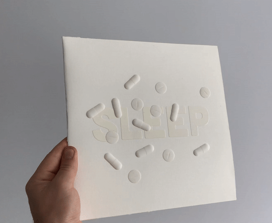 The SLEEP sleeve turning in the hand, light moving across its raised pills.