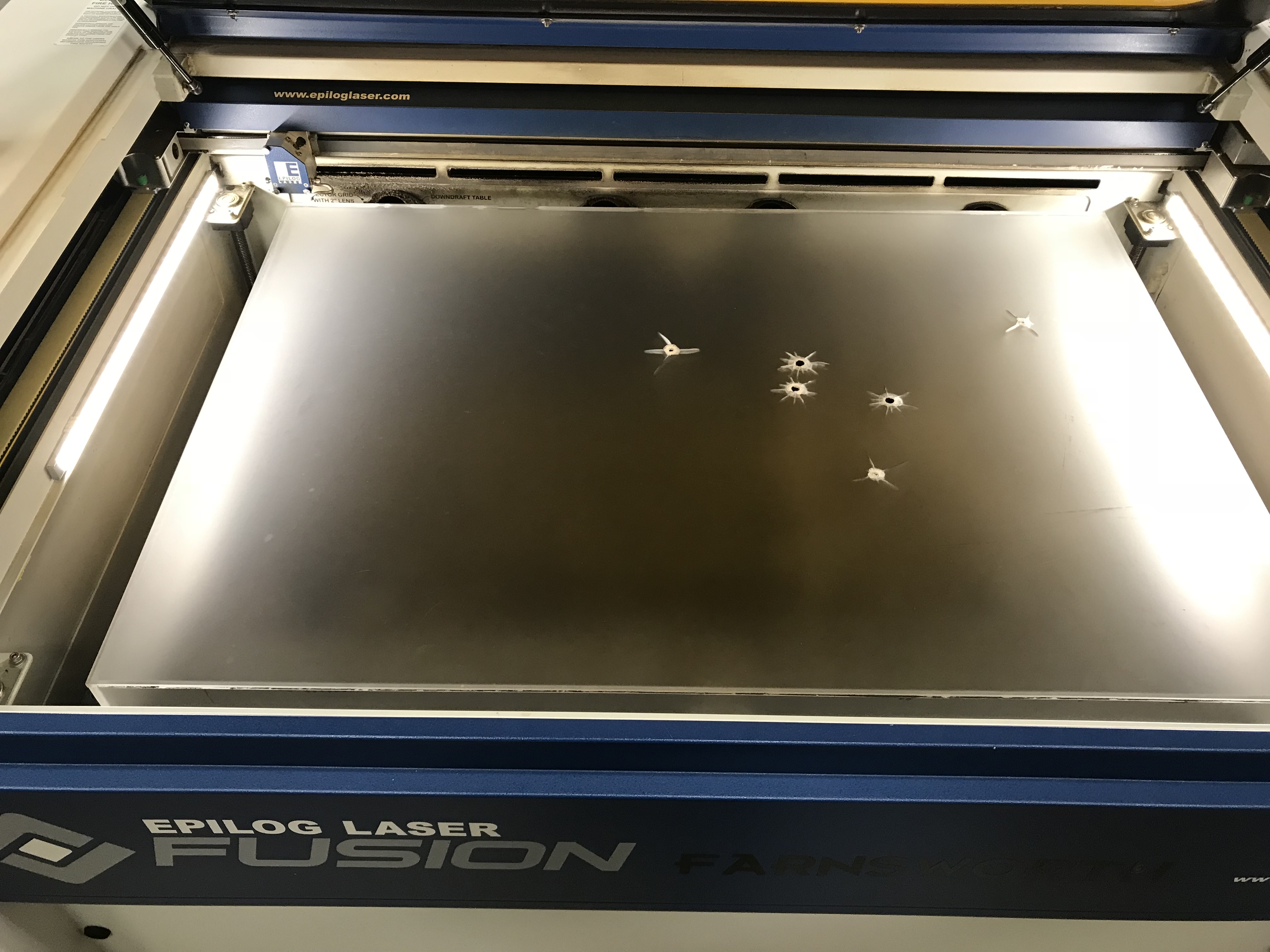 The frosted acrylic sheet lying in a laser cutter.
