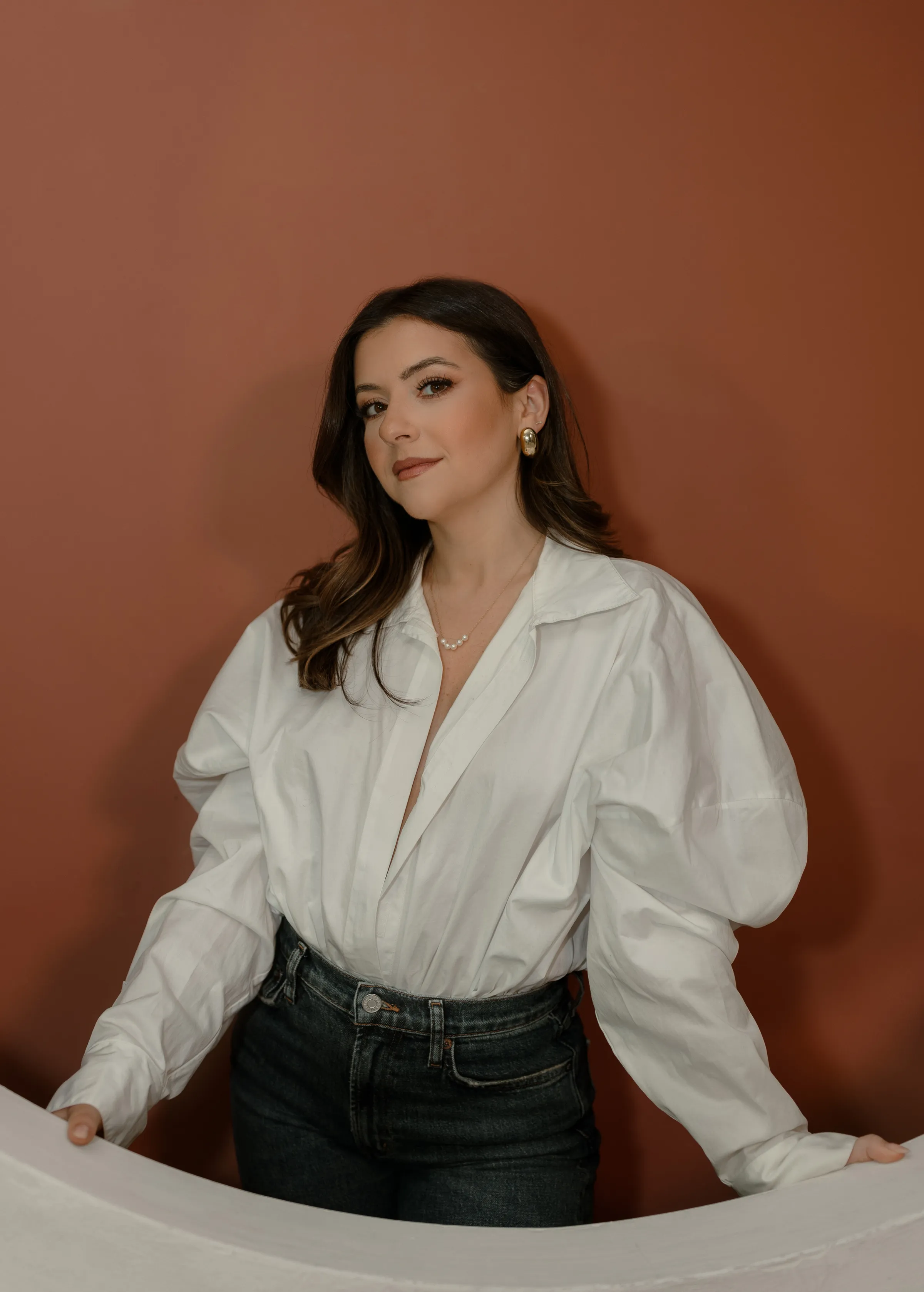 Giulia Guerrieri in a white shirt against a rust wall