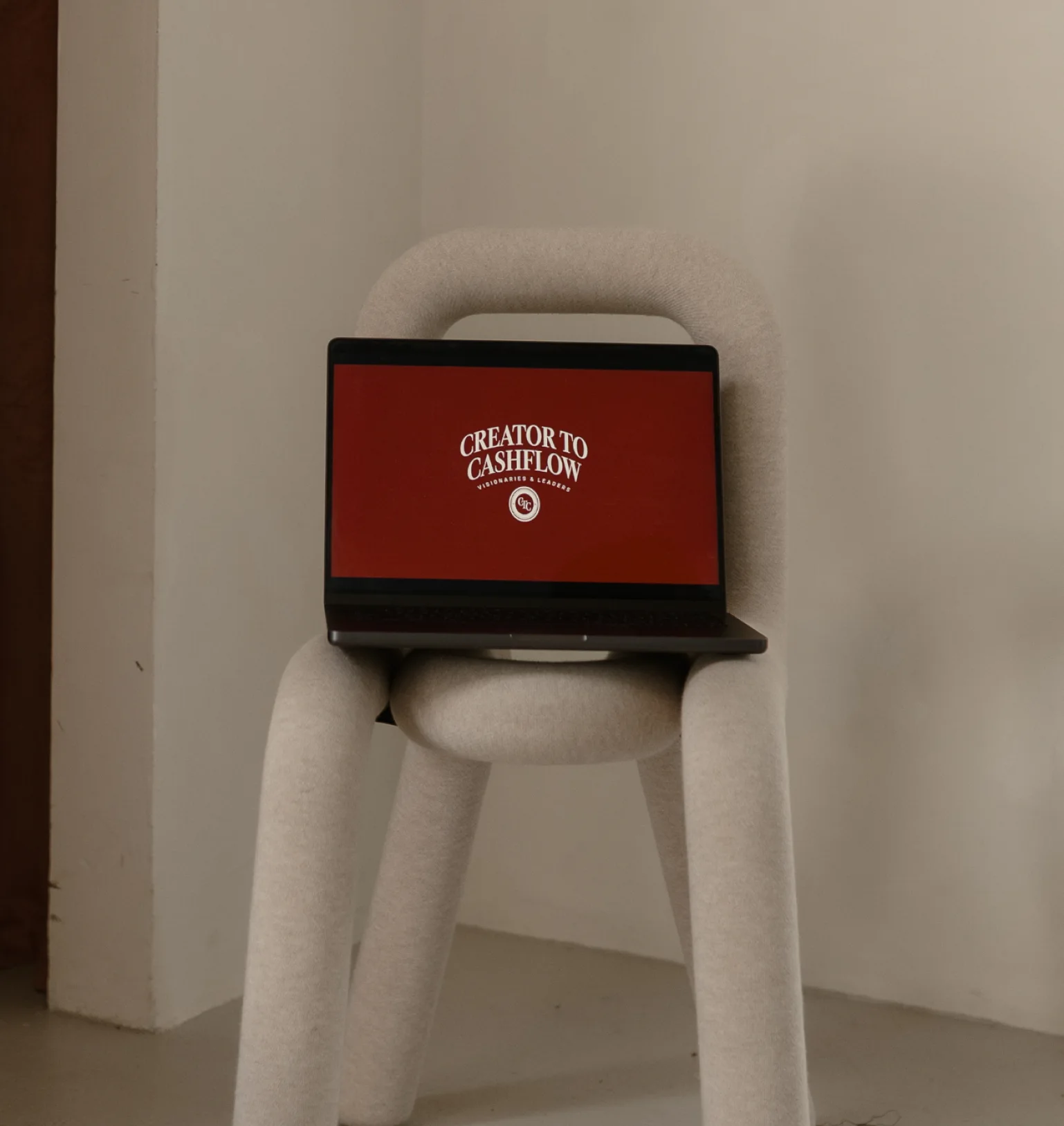 A laptop showing Creator to Cashflow on a white chair