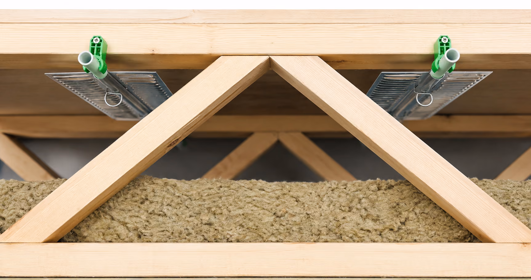 Wooden roof truss with green fasteners and thick fibrous insulation material inside.