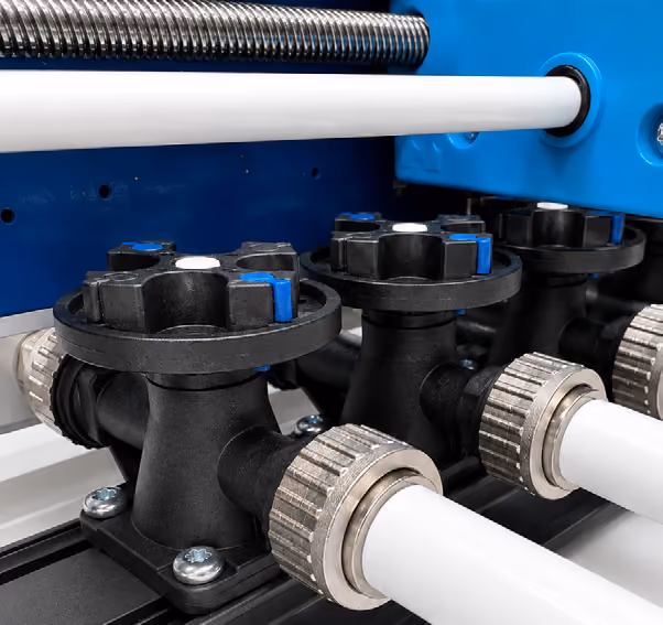 Close-up of black industrial valves connected to white pipes with metal fittings inside machinery.