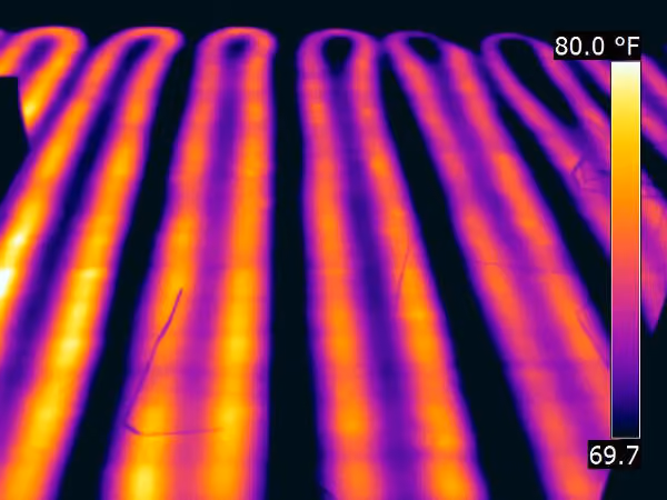 Infrared image showing floor radiant heating pipes with alternating warm yellow-orange and cooler purple areas, temperature scale from 69.7°F to 80.0°F visible on the right side.