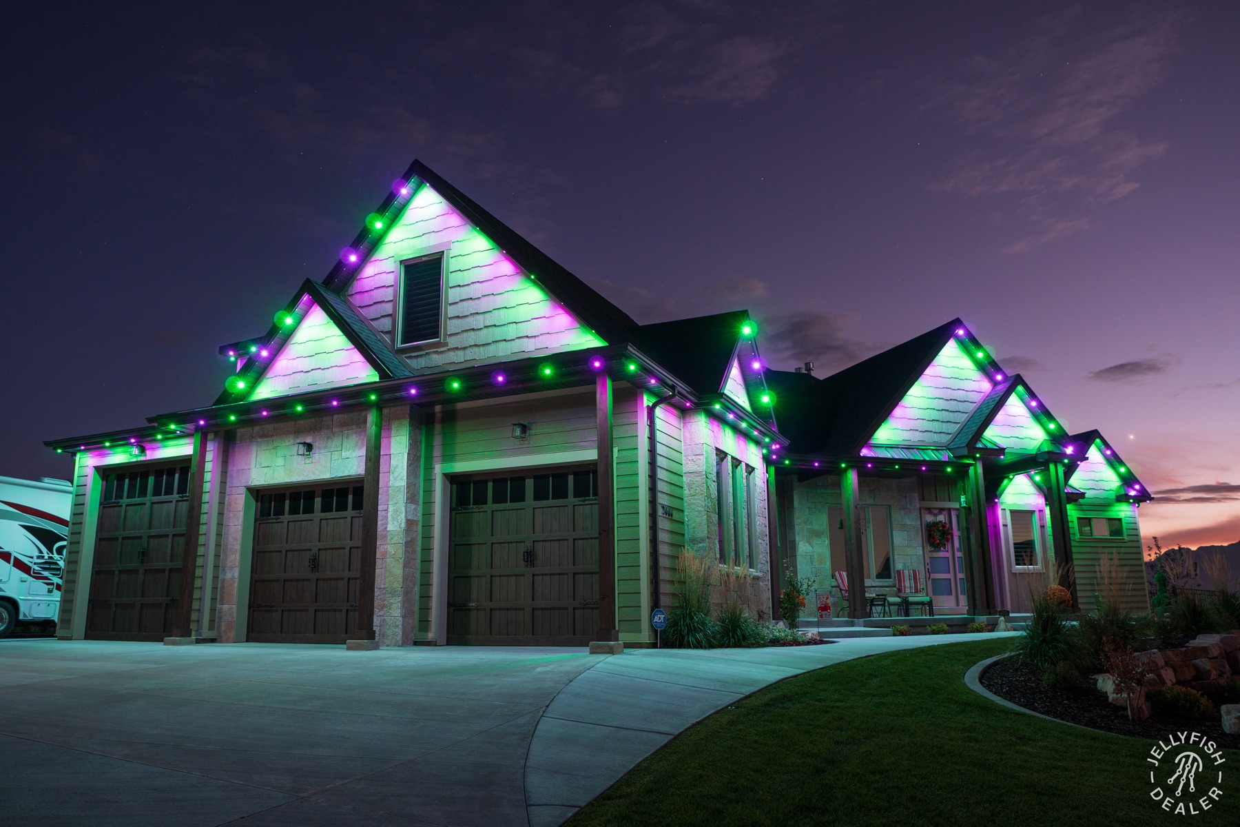 Green and purple JellyFish lights outlining a corner home at dusk.