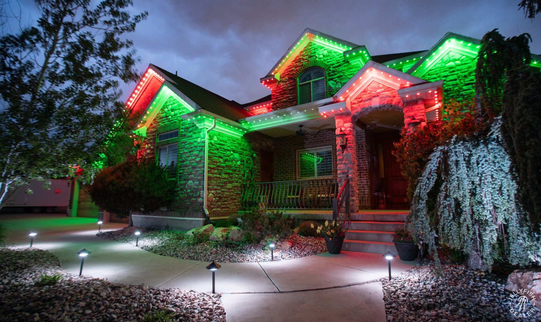 Red and green roofline lighting with illuminated landscaping.