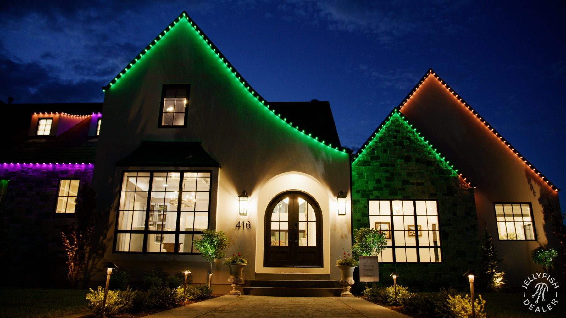 Orange, green and purple lighting on steep Halloween rooflines.