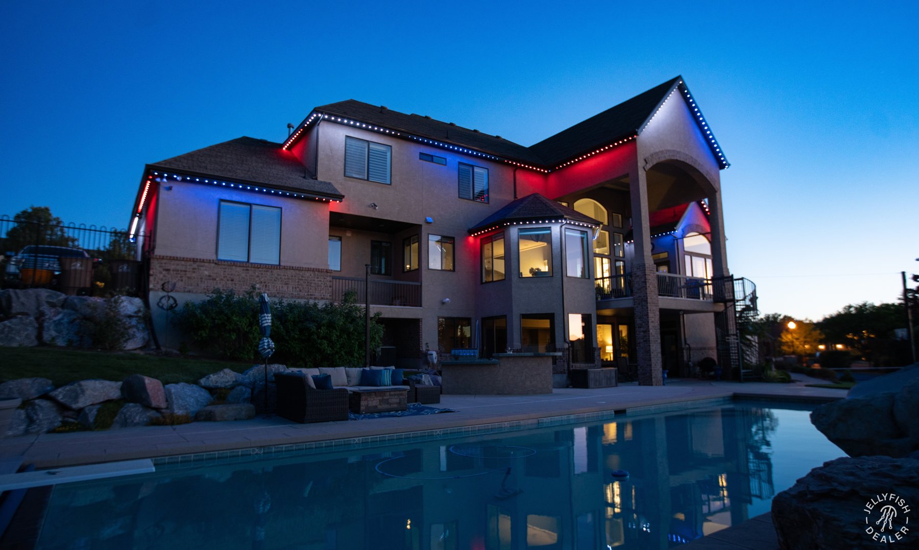 Patriotic lighting on a modern home overlooking a pool.