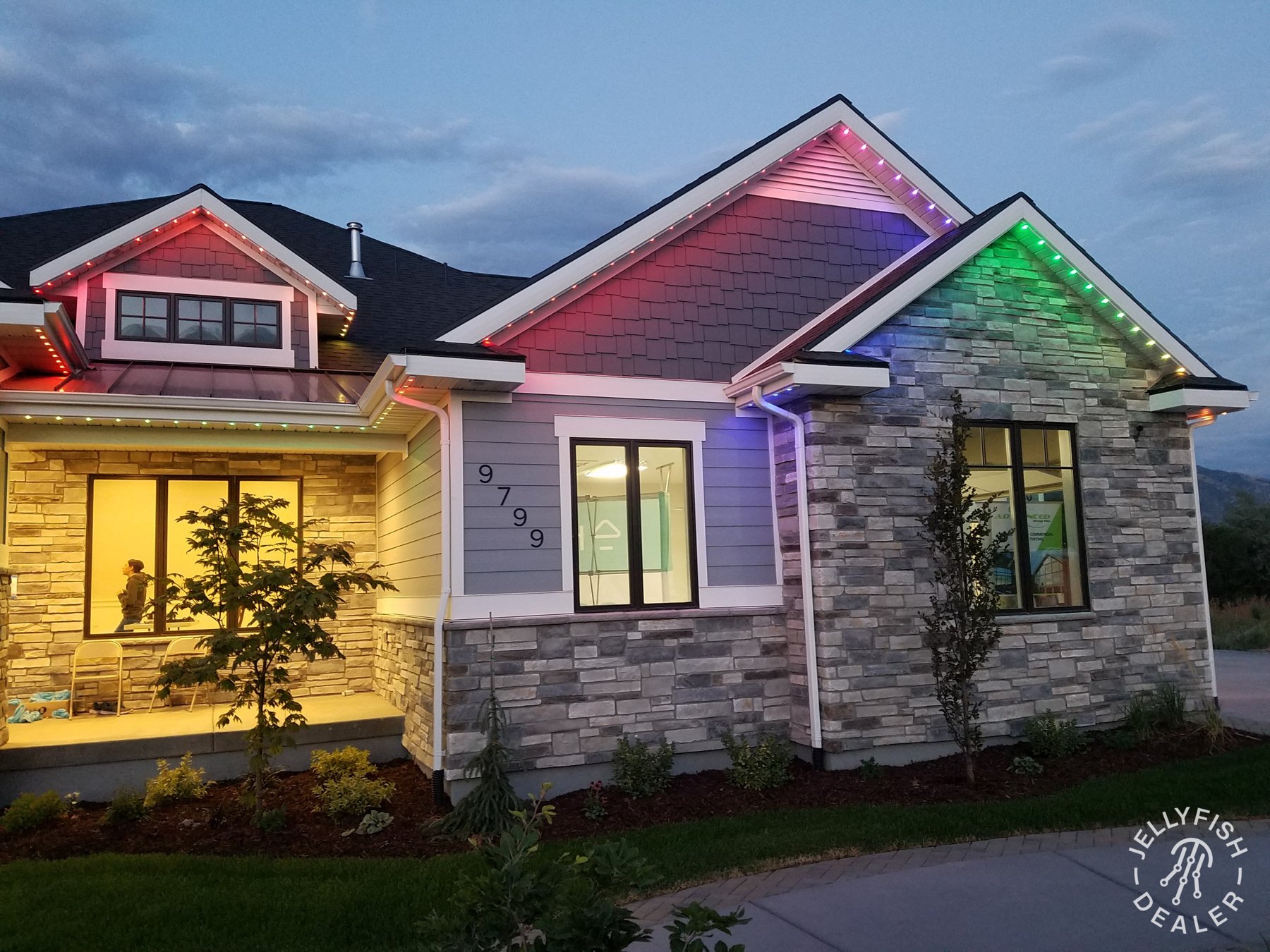 Multicolor JellyFish lighting along a gray home’s roofline.
