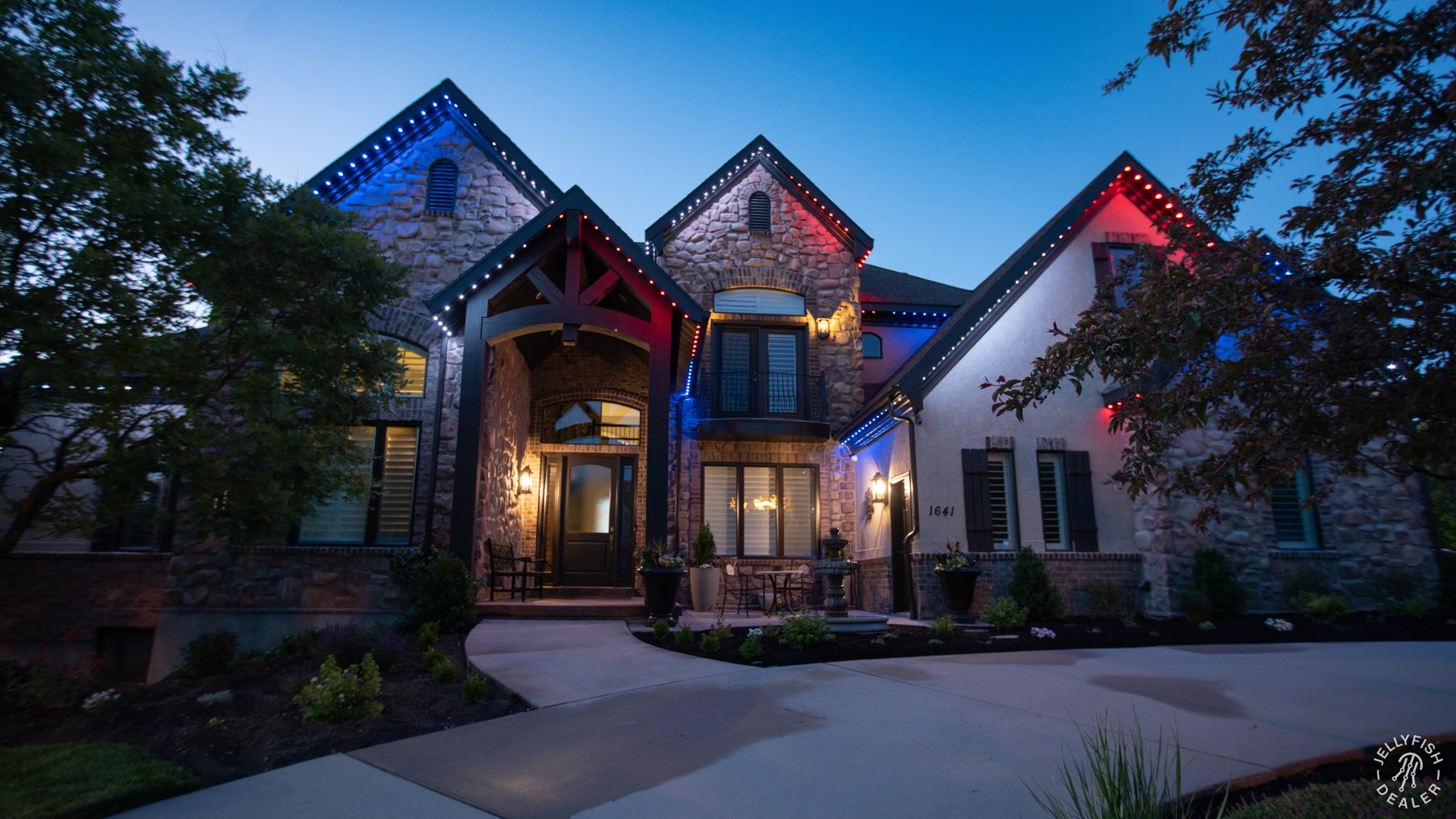 Red, white and blue lighting on a stone home at dusk.