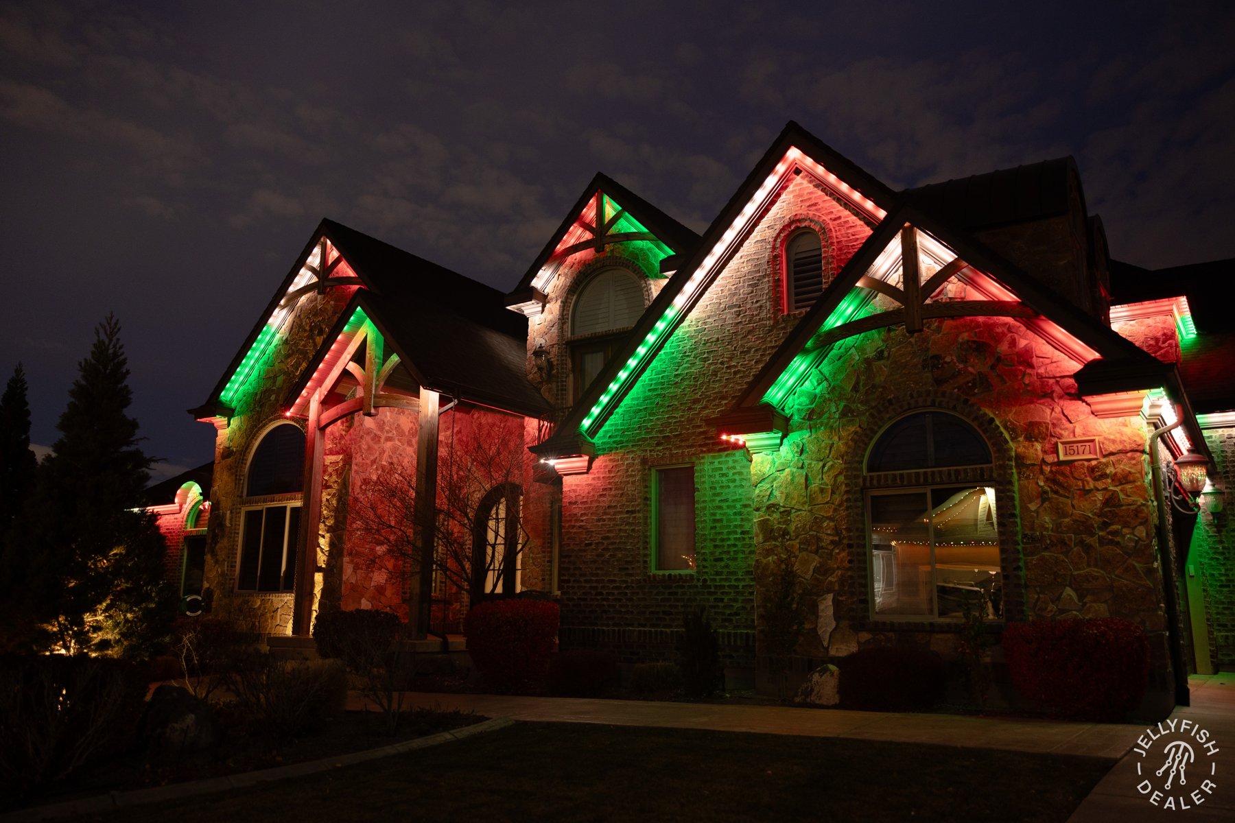 Red and green lights highlighting tall stone gables at night.