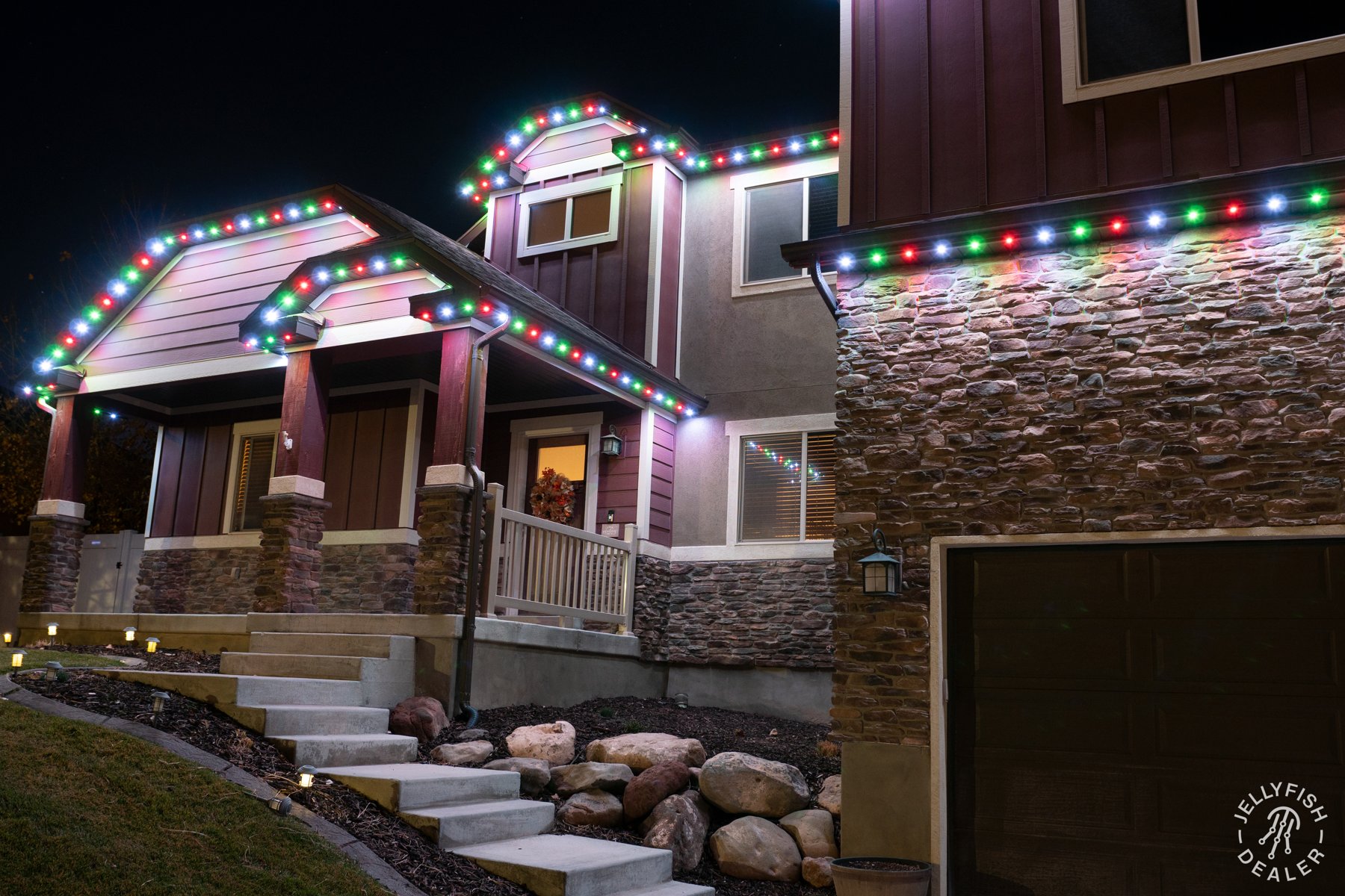 Multicolor Christmas lights along a two-story home and garage.