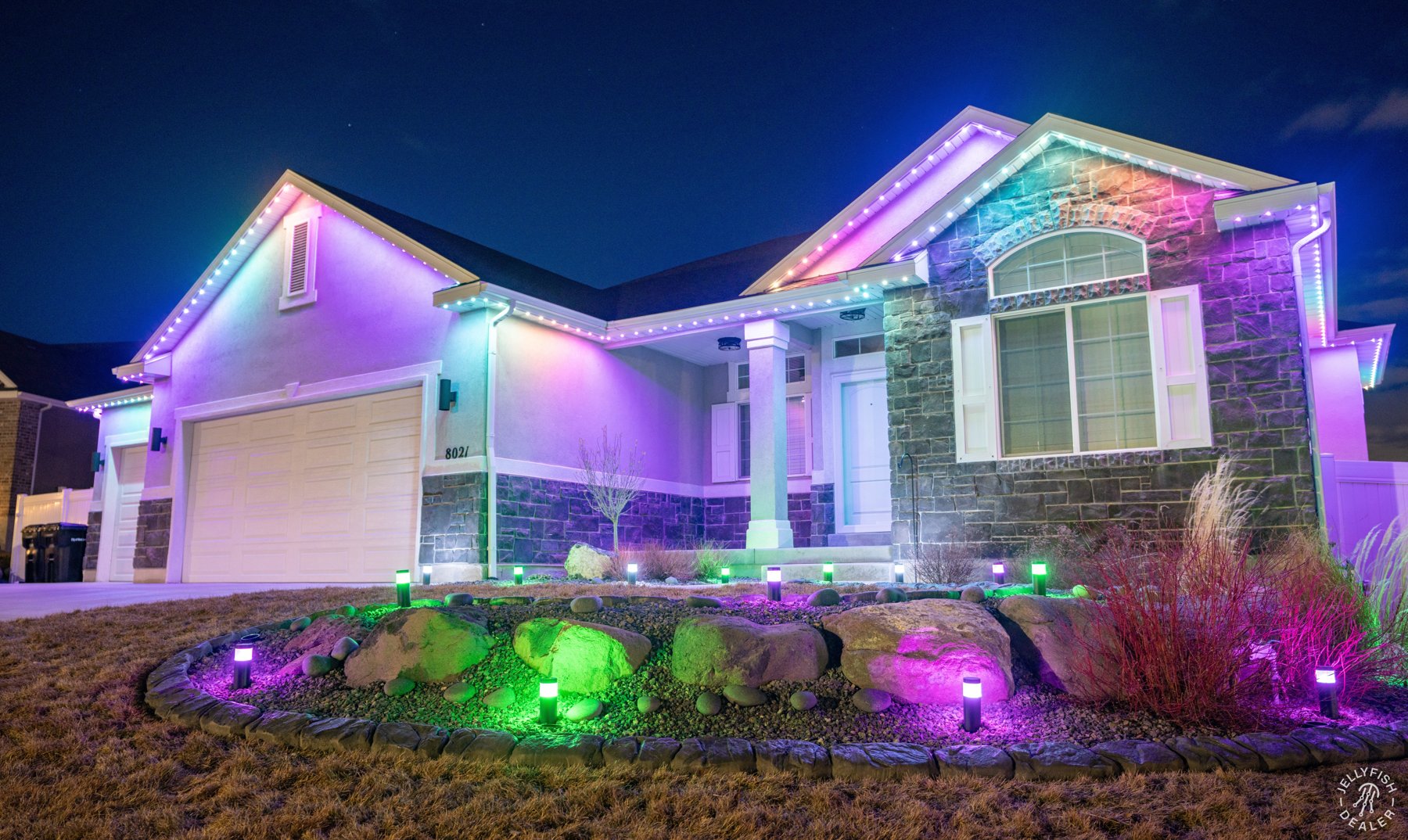 Rainbow roofline and garden lighting on a brick home.