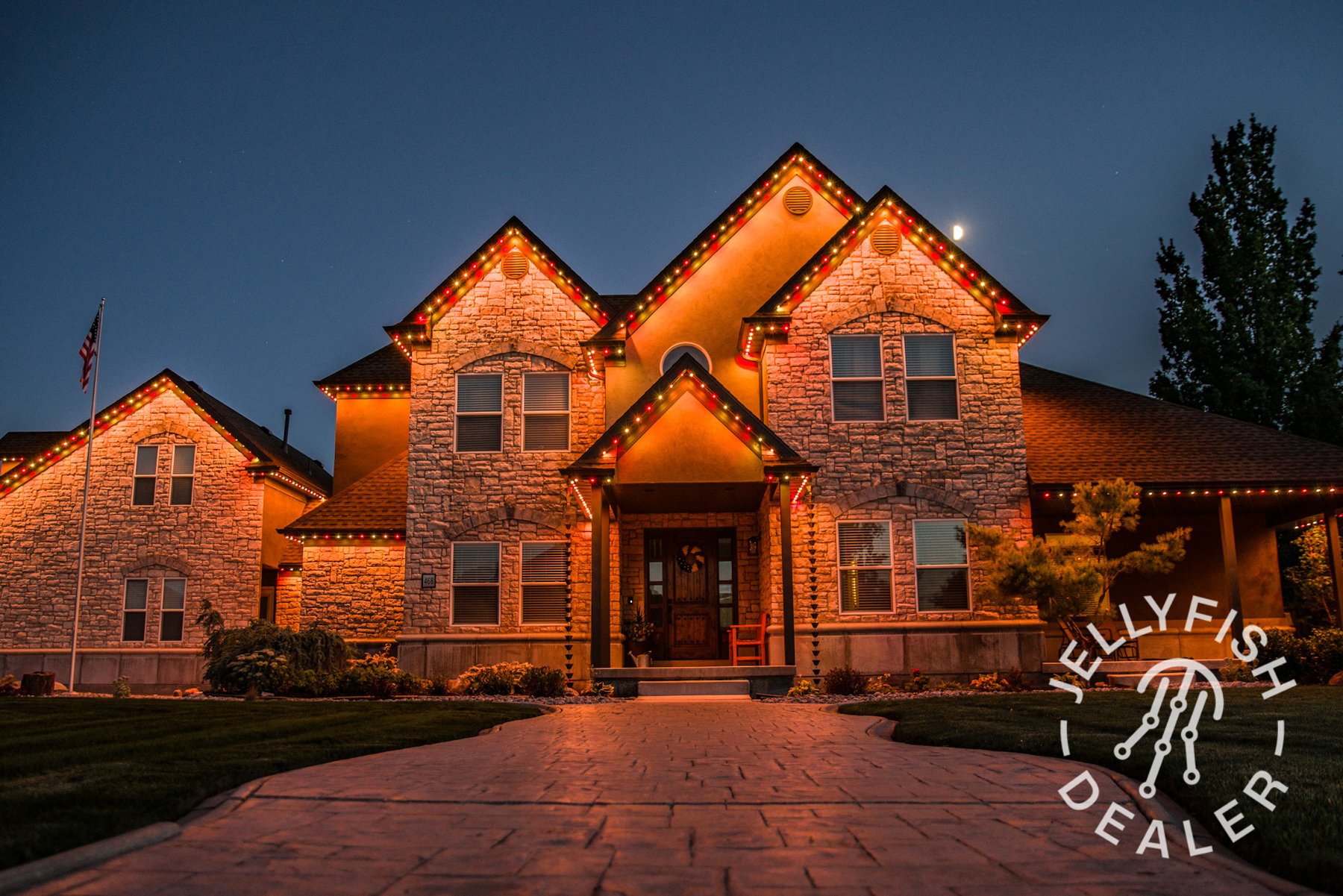 Amber lighting across a two-story brick home.
